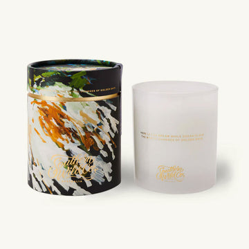 Frosted candle next to artistic packaging on a white background.