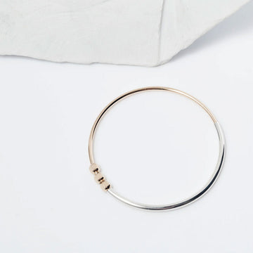 Gold and silver bangle on a light gray background.