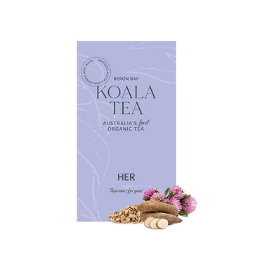 A purple tea box with dark green writing sitting behind some purple flowers and some sliced yams.