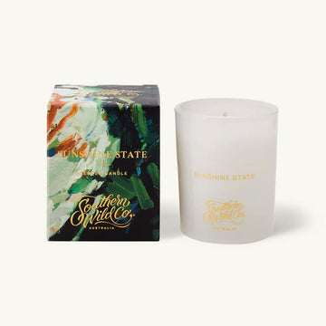 White candle with 'Southern Wild Co' branding next to its packaging on a white background.