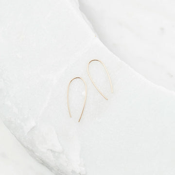 Gold hoop earrings on a white fabric background.
