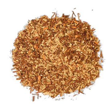 A purple tea box with dark green writing sitting behind some purple flowers and some sliced yams.