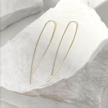 Gold hoop earrings on a white fabric background.