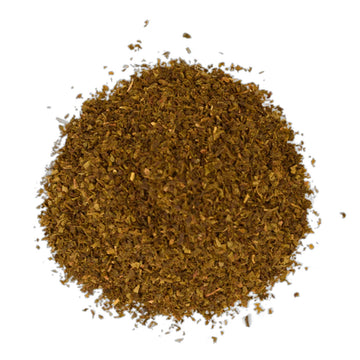 A green tea box with white writing sitting behind some ground green tea leaves.