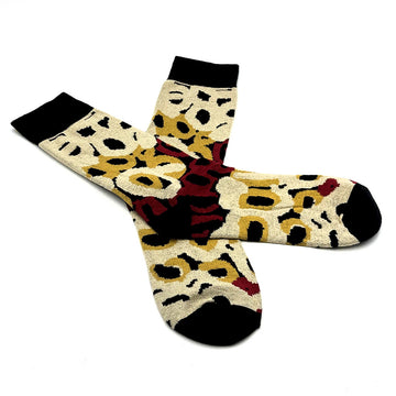  A pair of socks pictured with one overlaying the other. The socks are printed with artwork by Anmanari Brown.