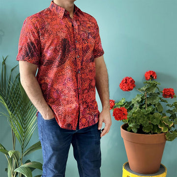 Front view of a model wearing a men's shirt printed with artwork by Andrea Adamson in shades of red and brown.