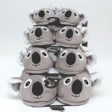Stack of gray koala plush slippers with black noses on a white background.