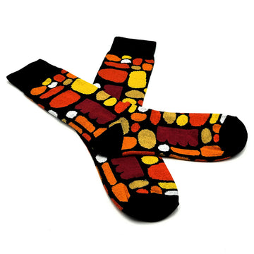 A pair of socks with one laying over the top of the other and printed with artwork by Ketura Nangala Zimran.