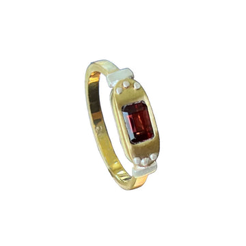A gold ring with a square red ruby in the centre with a large oval bezel design.