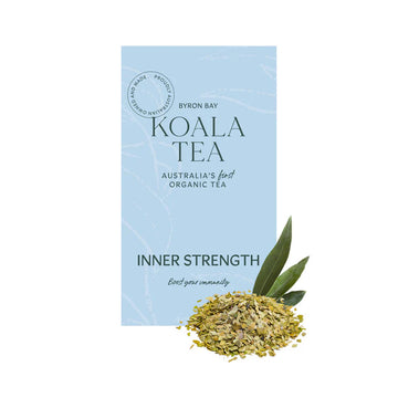 A light blue tea box with white writing sitting behind some loose leaf tea leaves.