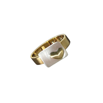 A gold ring with a silver rectangle and gold heart on the front.