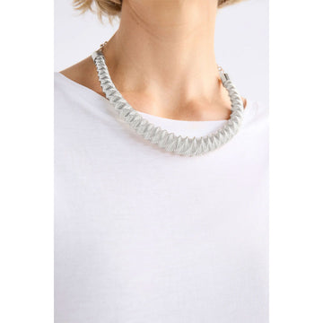 A gold necklace with zig zag shaped pattern.