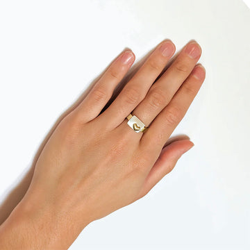 A gold ring with a silver rectangle and gold heart on the front.