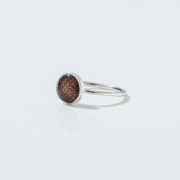 Silver ring with a brown gemstone on a light gray background.