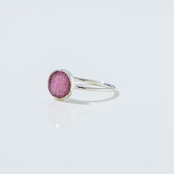 Silver ring with a pink gemstone on a light gray background.