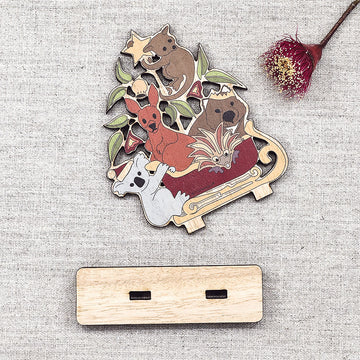 Wooden ornament of Australian animals riding a sleigh on a white background.