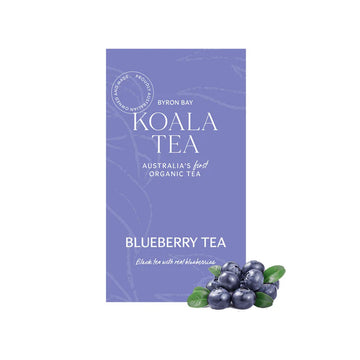 A purple box of tea sitting behind a bunch of blueberries.