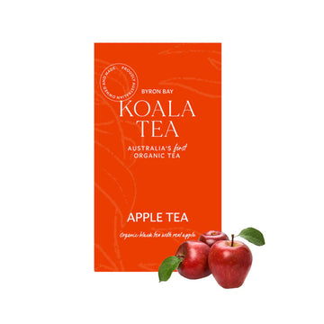 An orange box of tea with white writing sitting behind three apples.