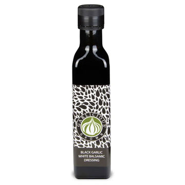 A black square bottle with a wide product label and the title 'Black Garlic White Balsamic Dressing'.