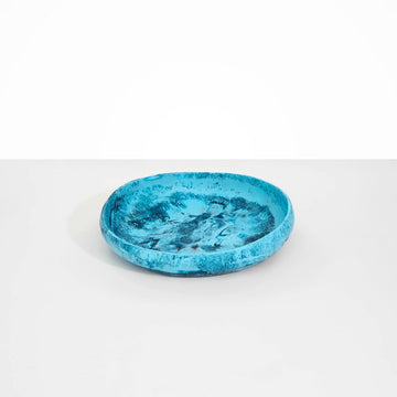 A round shallow bowl made from blue resin.