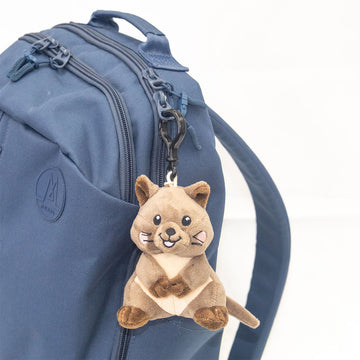 Blue backpack with a plush quokka keychain on a white background.