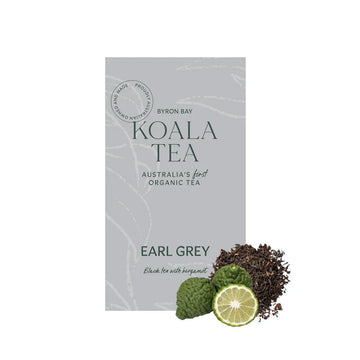 A grey box of tea with dark green text sitting behind some fruit and loose leaf tea.