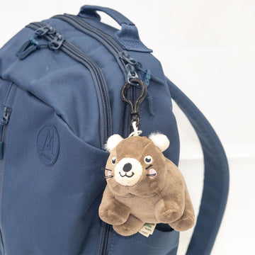 Blue backpack with a wombat-shaped keychain on a white background.