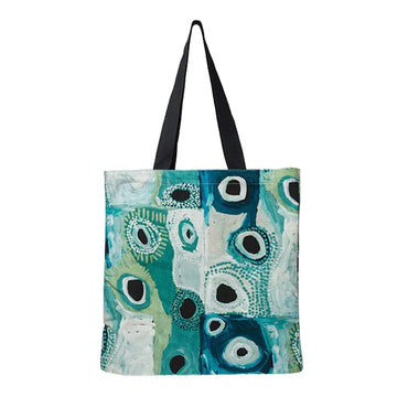 A tote bag printed with artwork by May Wokka Chapman in shades of blue and green.