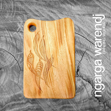 Wooden cutting board with engraved design of five gum leaves on a textured gray background, featuring the brand 'ngarga warendj'.