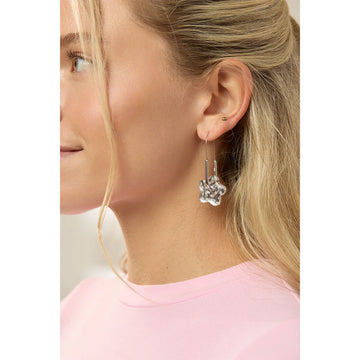 Silver earrings shaped like flowers on a hoop with polka dot design on a light gray background.