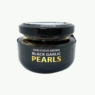 A small jar with a black product label and the title 'Garlicious Grown Black Garlic Pearls'.