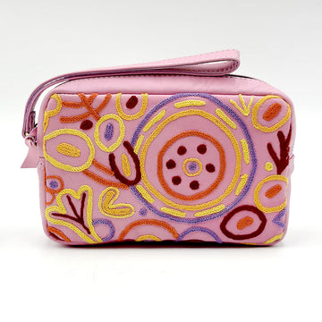 A pink leather toiletry bag embroidered with artwork by Cedric Varcoe with circles in yellow and purple.