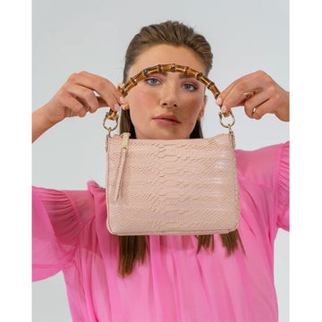 Front view of a bag with a top zipper and a blush snake texture with a round bamboo handle.