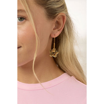Gold earrings shaped like flowers on a hoop with a polka dot design on a light gray background.
