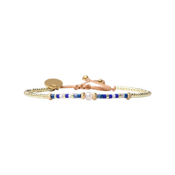 Gold bracelet with blue and white beads on a white background.