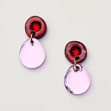 Pair of earrings with purple teardrop-shaped pendants and red gemstones on a light gray background.