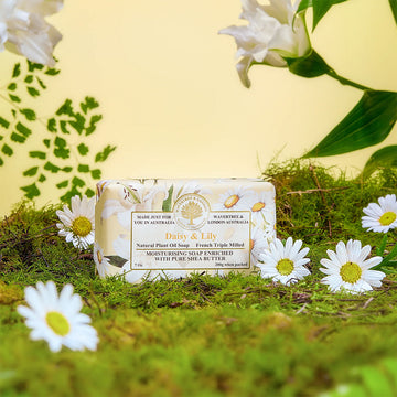 A bar of soap wrapped in paper with the heading 'Daisy and Lily' with daisies and lilies in the background.
