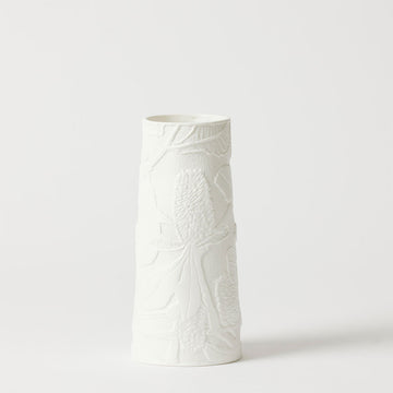 A tall triangular cylinder vase in white porcelain embossed with banksia flowers.