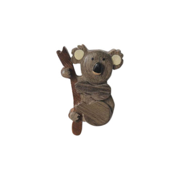 A timber magnet shaped like a koala holding a branch.