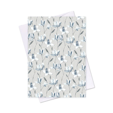 A card printed with magnolia blooms and a white envelope behind.