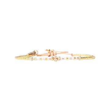 Gold bracelet with small beads on a white background.