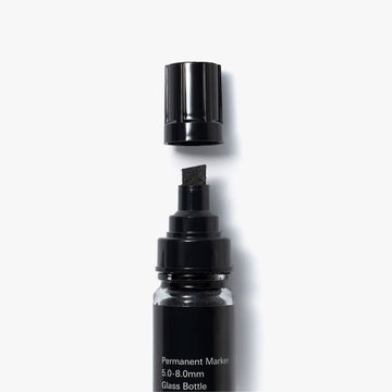 A small glass bottle with a black lid and filled with black ink.