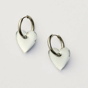 Heart-shaped earrings with silver hoops on a light gray background.