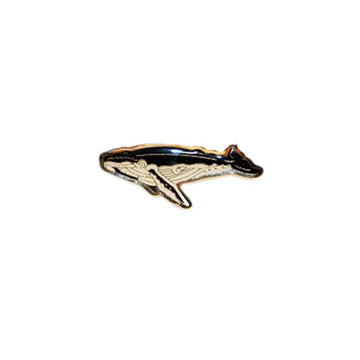 A badge in the shape of a whale swimming.