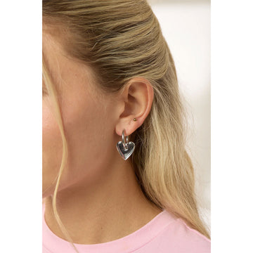 Heart-shaped earrings with silver hoops on a light gray background.