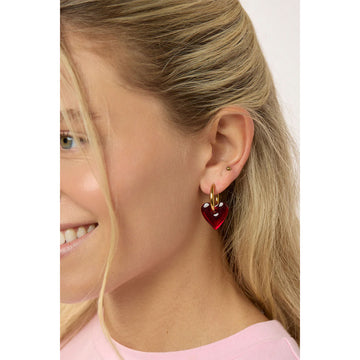Heart-shaped red earrings with gold hoops on a light gray background.