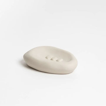 A ceramic dish in a bone colour and irregular oval shape.