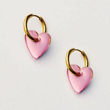 Pink heart-shaped earrings with gold hoops on a light gray background.