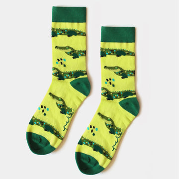 A pair of light green socks with an dark green heel, toe and cuff illustrated with crocodiles.