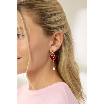 Heart-shaped earrings with gold hoops and pearl drops on a light gray background.